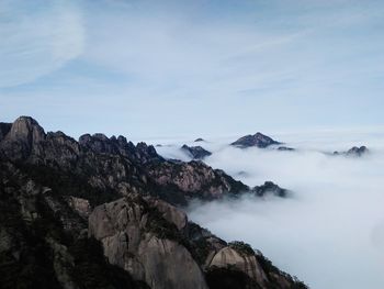 Scenic view of mountains amidst fog against sky