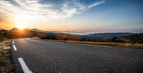 Surface level of road against sky during sunset