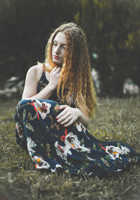 Young woman sitting on grassy field at park