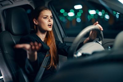 Irritated young woman driving car