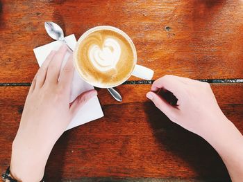 Hand holding coffee cup on table