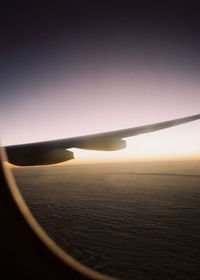 Airplane flying in sky at sunset