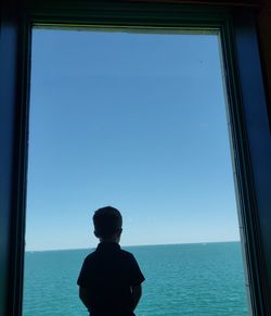 Rear view of man looking at sea against sky