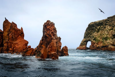 Rock formations in sea against sky