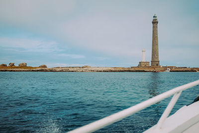 Lighthouse by sea against sky