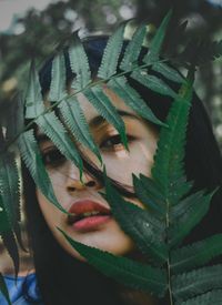 Close-up portrait of young woman by leaves