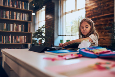 Girl reading book in school library. child doing homework in after school club. back to school