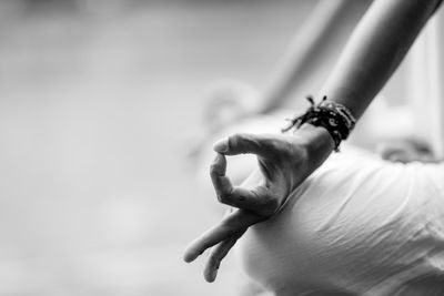 Midsection of woman meditating in lotus position at lakeshore