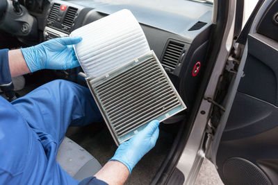 Midsection of man repairing air conditioner in car