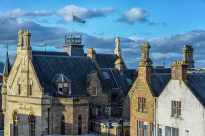 View of rooftops and chimneys of mansions against cloudy  sky. 