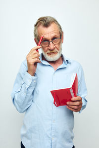 Young man using mobile phone while standing against white background