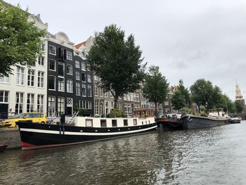 Boats in canal by buildings against sky