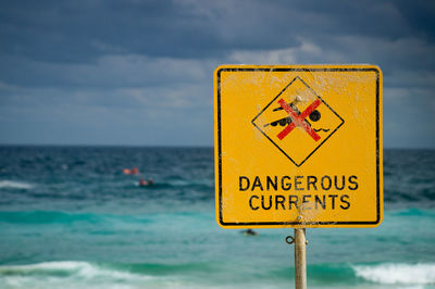 Close-up warning sign against sea