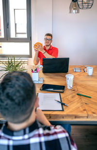 Smiling businessman holding small basket ball and having fun playing with colleague in office