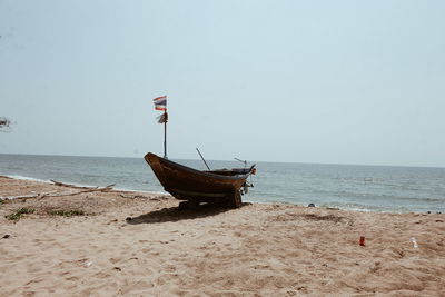 Boat moored on beach against clear sky