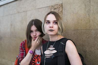 Females friends standing by retaining wall