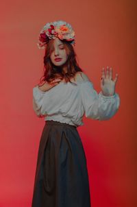 Side view of young woman standing against red background