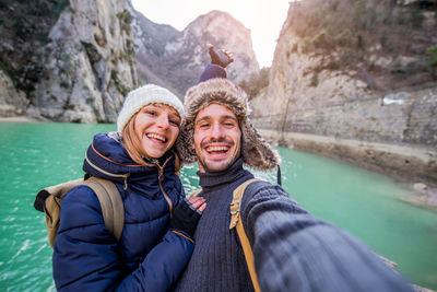 Portrait of smiling couple standing against lake
