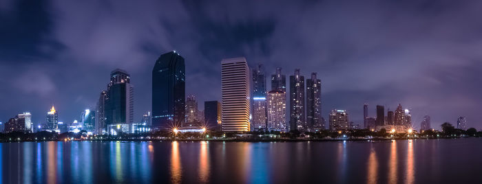 Panoramic view of illuminated city by river at night