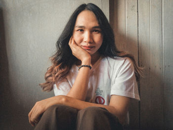 Portrait of woman sitting against wall