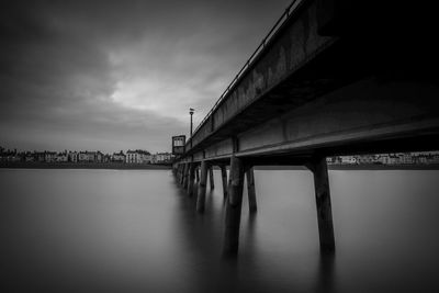 Bridge over sea against cloudy sky