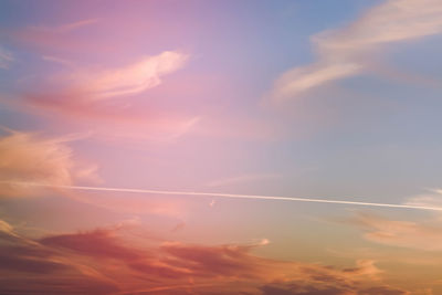 Low angle view of vapor trail in sky during sunset