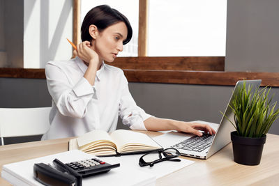 Young woman using mobile phone on table