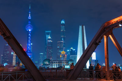 Illuminated skyscrapers seen from bridge in city at night