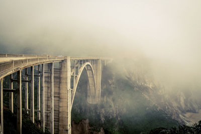 Arch bridge against sky during foggy weather