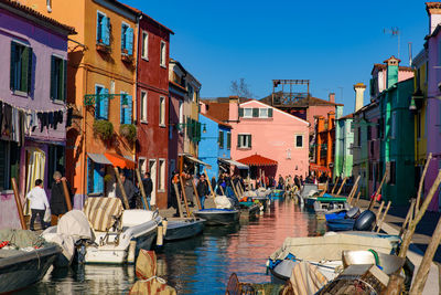 Boats moored in canal by buildings in city against sky