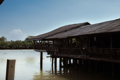 Wooden house by lake against sky