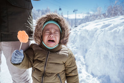 Portrait of smiling boy standing on snow covered landscape