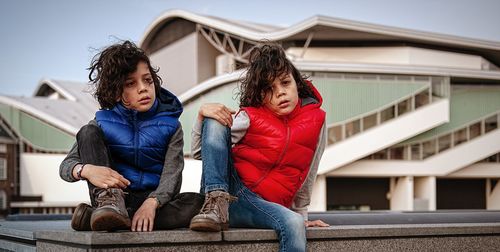 Full length of boys sitting on built structure