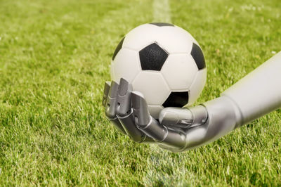 Robot arm reaches out to a football. soccer playing with machine. robot arm and soccer grass field.