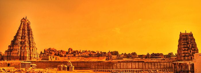Cranes at temple against sky during sunset