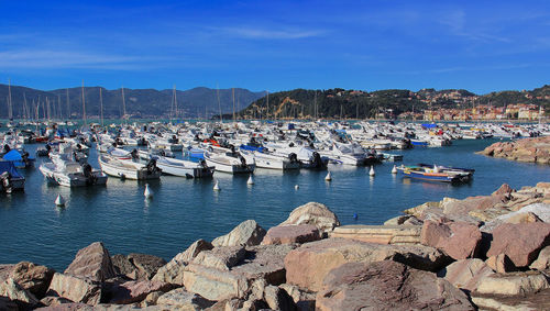 Sailboats moored in harbor against blue sky