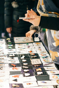 Midsection of woman using phone by decorations on stall for sale