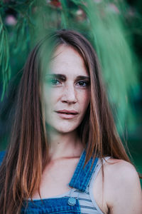 Portrait of young woman standing against plants at park