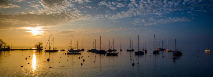 Boats moored in calm sea at sunset