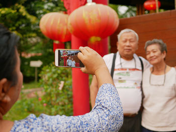 Rear view of woman photographing couple outdoors