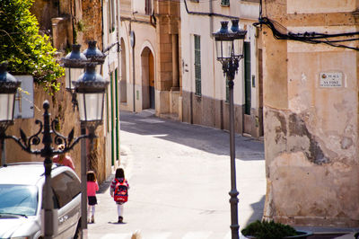 Rear view of people walking on street amidst buildings