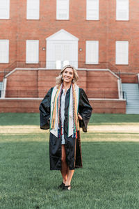 Full length portrait of teenage girl standing against brick wall