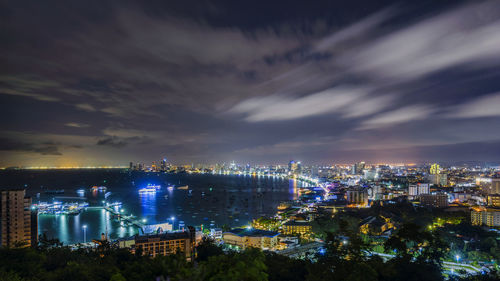 Aerial view of illuminated buildings against cloudy sky