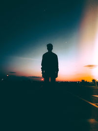 Rear view of silhouette man standing against sky at night