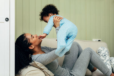 Mother playing with son while sitting on sofa at home