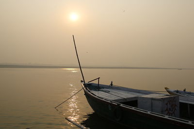 Boat moored in sea against clear sky during sunset