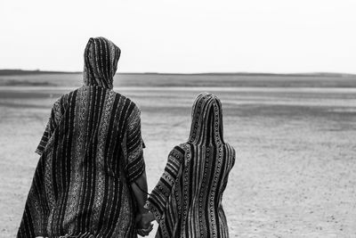 Rear view of woman and girl on field against sky