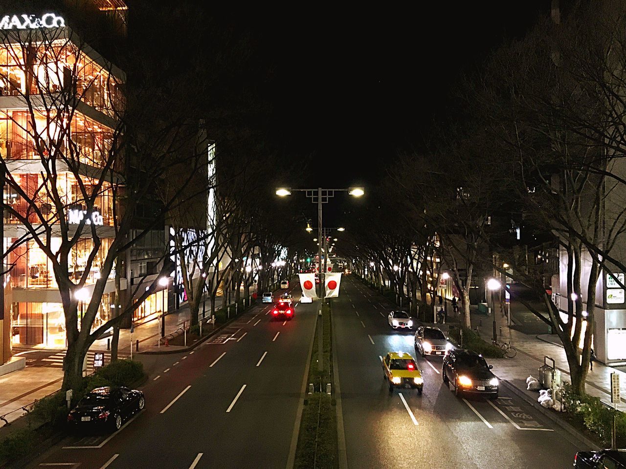 CARS ON ILLUMINATED CITY STREET AT NIGHT