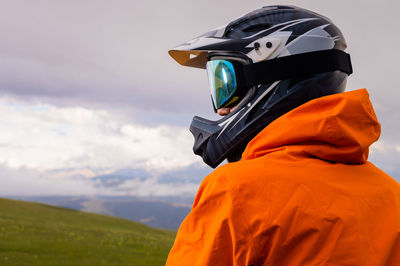 Rear view of man wearing hat standing on field against sky