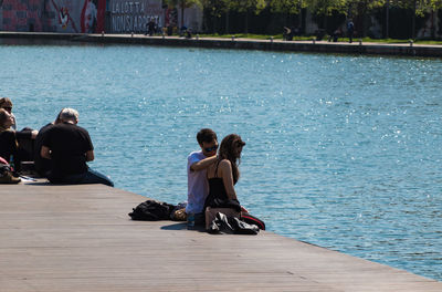 Rear view of people sitting on shore